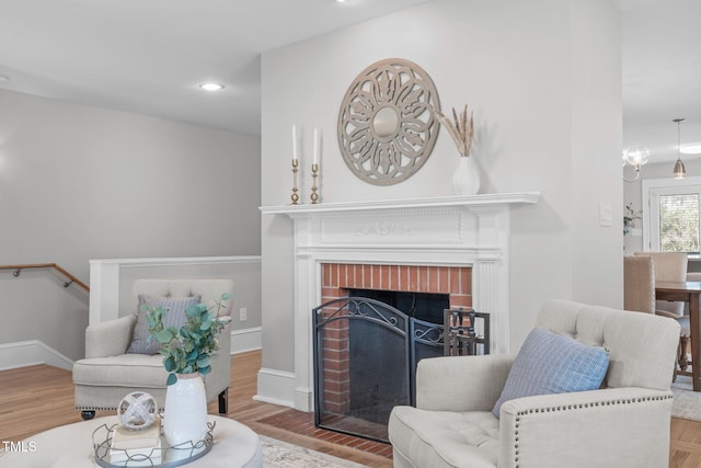 living room featuring recessed lighting, a brick fireplace, baseboards, and wood finished floors