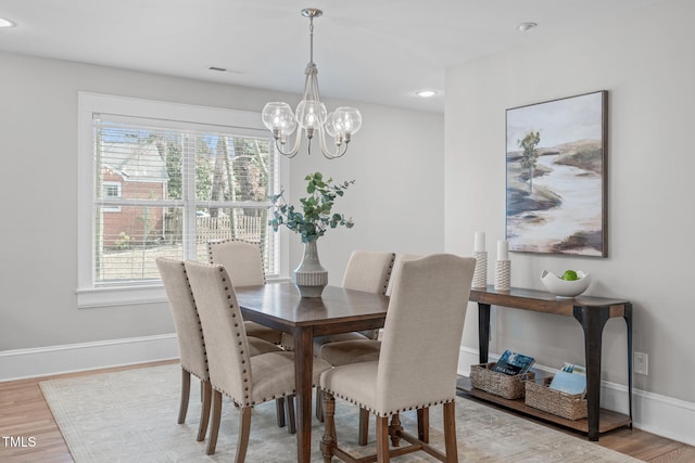 dining room featuring visible vents, baseboards, light wood-type flooring, and an inviting chandelier