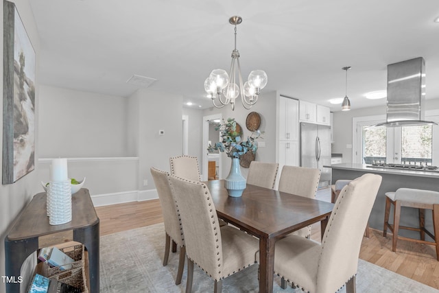 dining room with baseboards, light wood-style floors, and an inviting chandelier