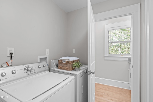 clothes washing area featuring laundry area, baseboards, light wood-type flooring, and washer and clothes dryer