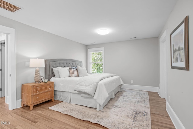 bedroom featuring visible vents, baseboards, and light wood finished floors