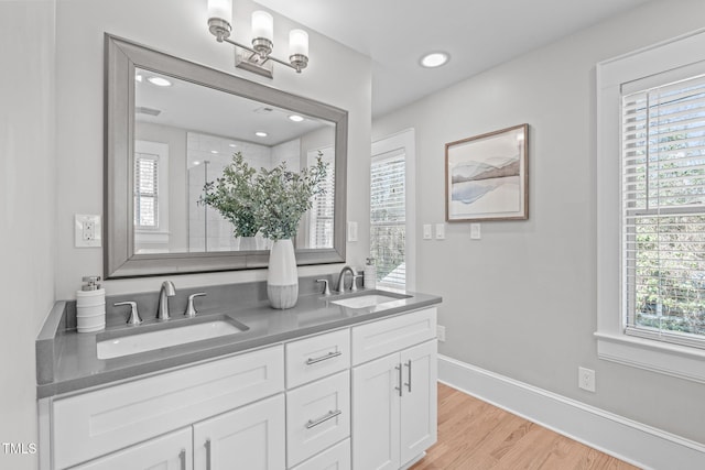 bathroom featuring double vanity, wood finished floors, baseboards, and a sink