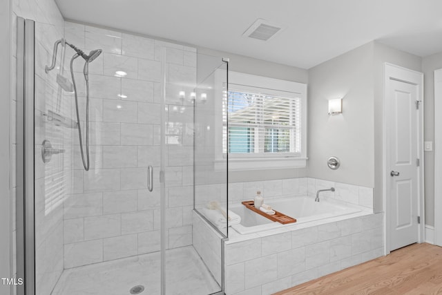 bathroom featuring visible vents, wood finished floors, a garden tub, and a stall shower