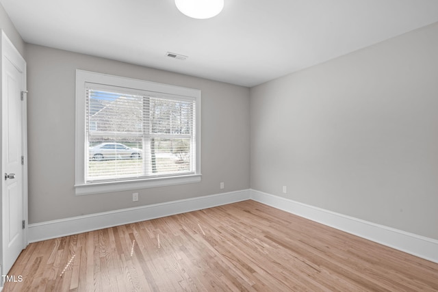 empty room with light wood-type flooring, visible vents, and baseboards