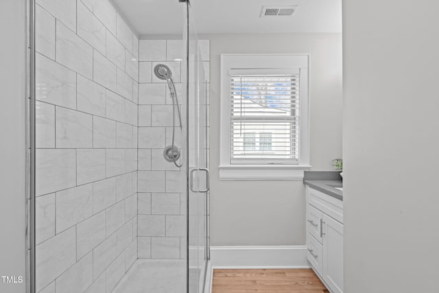 full bath with visible vents, a shower stall, baseboards, wood finished floors, and vanity