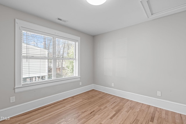 unfurnished room featuring light wood finished floors, visible vents, attic access, and baseboards