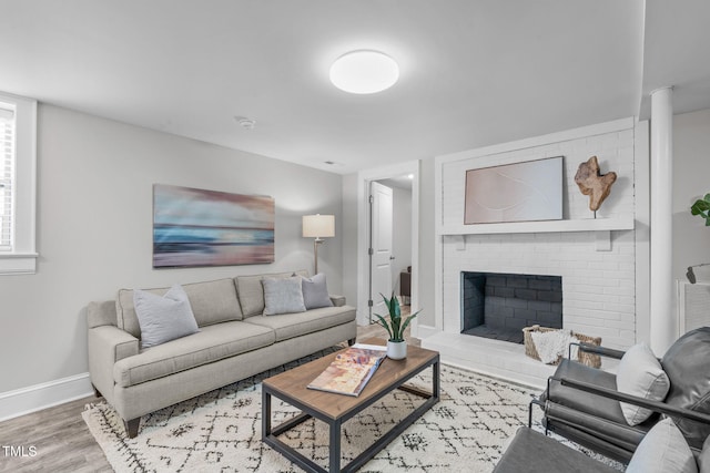 living area with a brick fireplace, wood finished floors, and baseboards