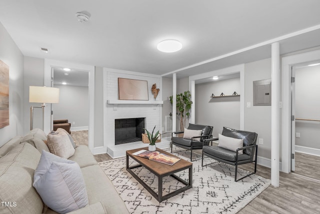 living room featuring light wood finished floors, a fireplace, electric panel, and baseboards