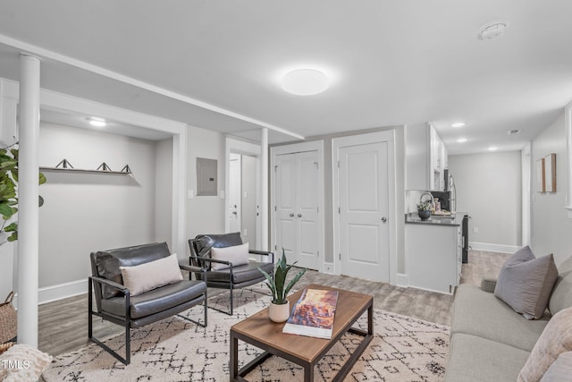 living area featuring recessed lighting, electric panel, baseboards, and light wood-type flooring