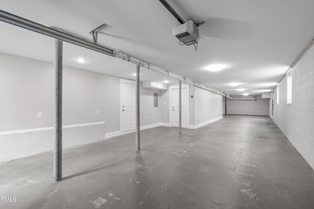 garage featuring electric panel, a garage door opener, and concrete block wall