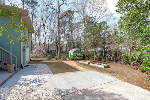 view of yard with concrete driveway, a garden, and an outbuilding