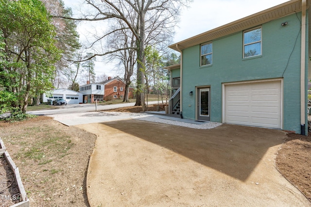 exterior space with brick siding, stairway, concrete driveway, and a garage