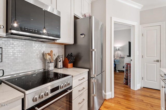 kitchen with light wood-style flooring, ornamental molding, white cabinetry, stainless steel appliances, and light stone countertops