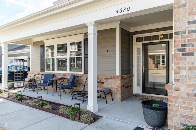 entrance to property featuring brick siding and covered porch