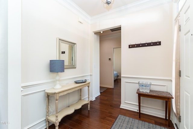 hall featuring crown molding, a decorative wall, wood finished floors, and a wainscoted wall