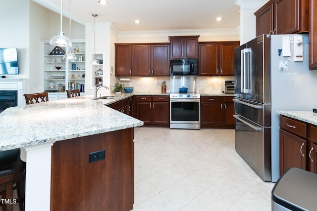 kitchen with a sink, light stone counters, appliances with stainless steel finishes, a breakfast bar area, and a peninsula