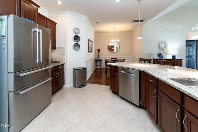 kitchen featuring light stone counters, appliances with stainless steel finishes, pendant lighting, crown molding, and tasteful backsplash