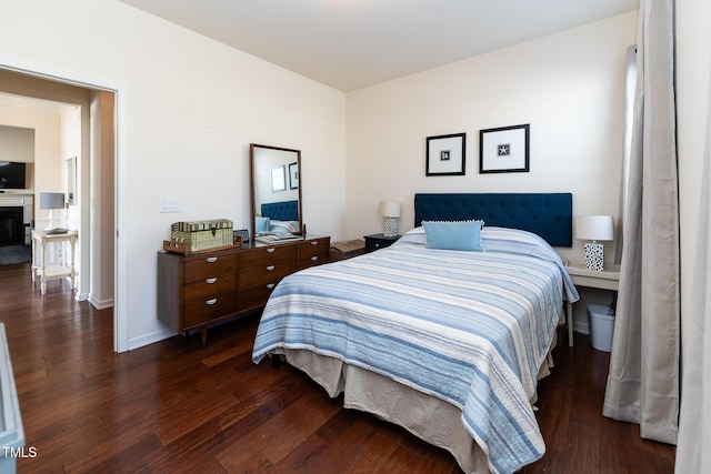 bedroom featuring a fireplace, baseboards, and wood finished floors