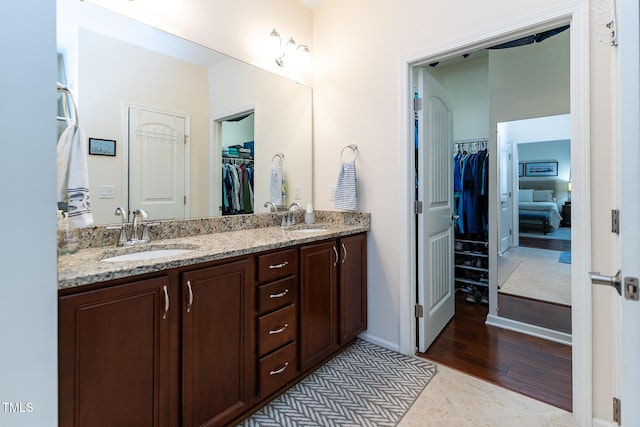 full bathroom featuring double vanity, a spacious closet, baseboards, and a sink