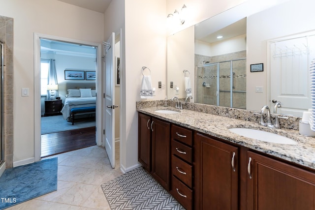 ensuite bathroom with double vanity, a shower stall, connected bathroom, and a sink