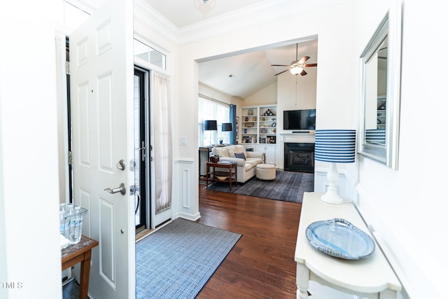 foyer entrance featuring a ceiling fan, lofted ceiling, a fireplace, dark wood-style flooring, and crown molding