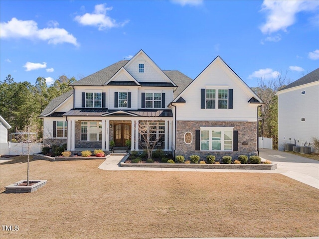 view of front of home featuring fence, driveway, a standing seam roof, stone siding, and metal roof