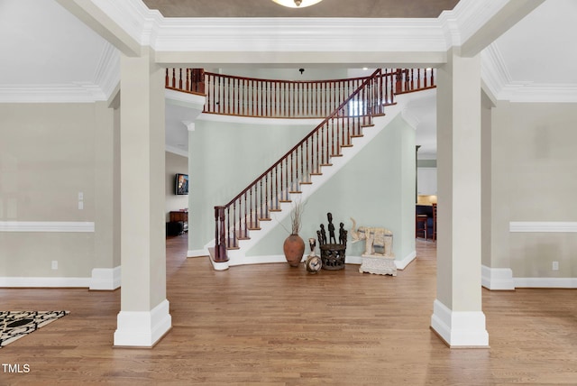 stairs featuring decorative columns, baseboards, wood finished floors, and crown molding