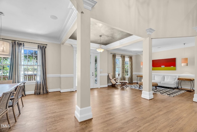 foyer entrance with a wealth of natural light, crown molding, ornate columns, and wood finished floors