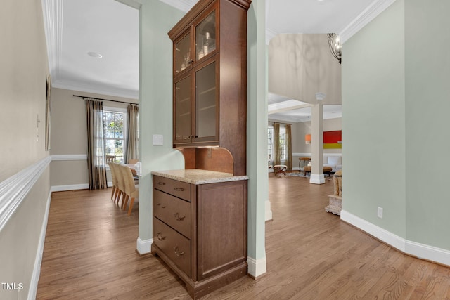 corridor featuring baseboards, light wood-style floors, and crown molding