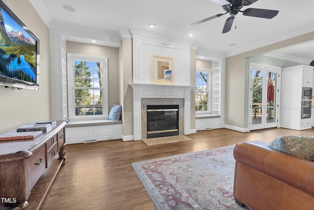 living area featuring baseboards, wood finished floors, a fireplace, and crown molding