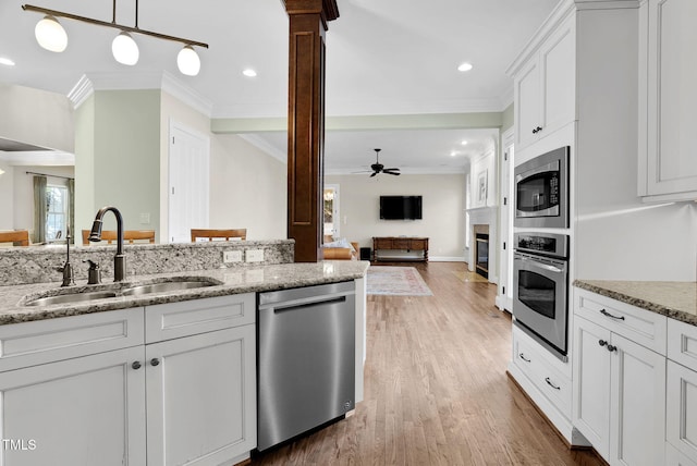 kitchen with appliances with stainless steel finishes, white cabinetry, crown molding, and a sink