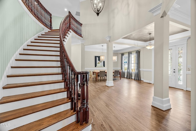 entryway featuring crown molding, decorative columns, and wood finished floors