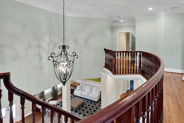 staircase featuring baseboards, a notable chandelier, wood finished floors, and crown molding