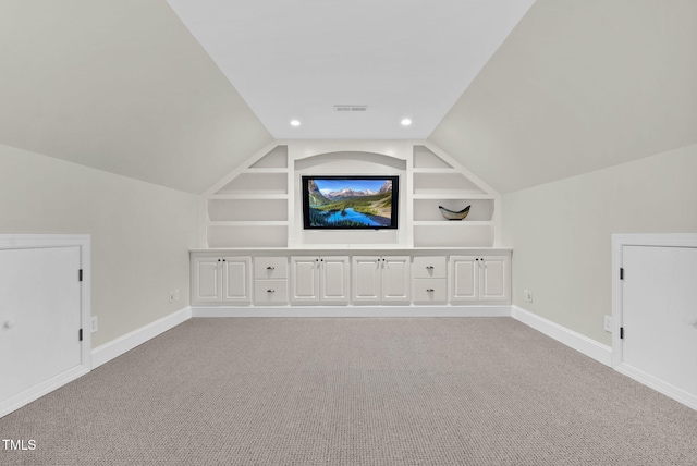 additional living space with baseboards, built in shelves, light carpet, and vaulted ceiling