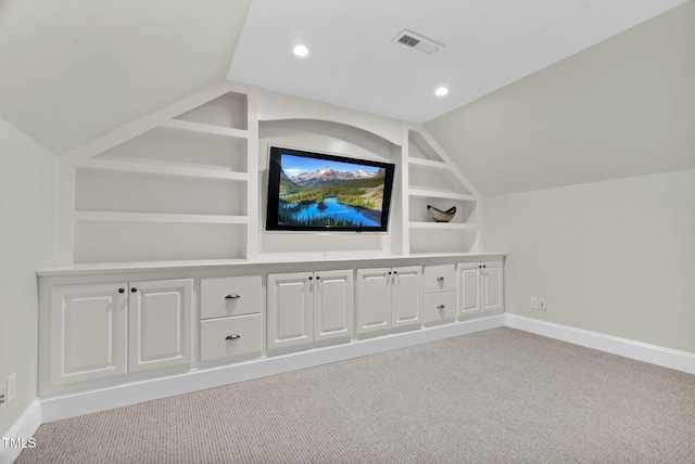 interior space featuring built in shelves, carpet, visible vents, baseboards, and lofted ceiling