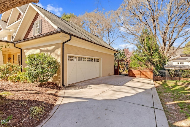 view of property exterior with brick siding, an attached garage, driveway, and fence