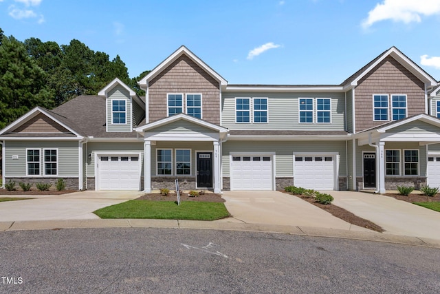 view of front facade featuring stone siding, driveway, and an attached garage