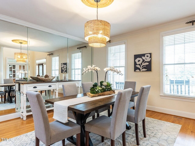 dining space with visible vents, light wood-style floors, an inviting chandelier, crown molding, and baseboards