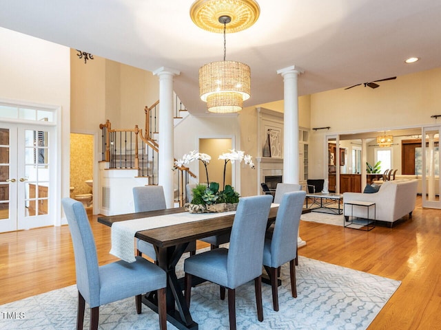 dining room with ornate columns, light wood-style floors, and an inviting chandelier