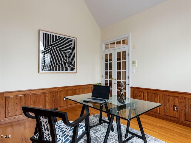 office space with a wainscoted wall, light wood finished floors, vaulted ceiling, and french doors