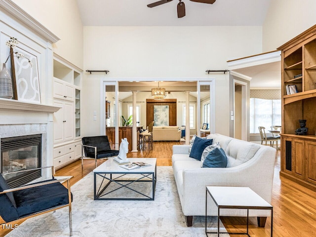 living area featuring a glass covered fireplace, lofted ceiling, wood finished floors, and ceiling fan