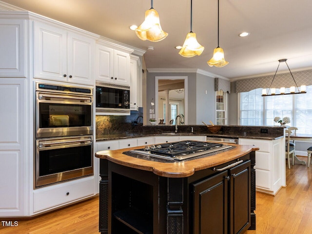 kitchen featuring ornamental molding, white cabinets, stainless steel appliances, wood counters, and a sink