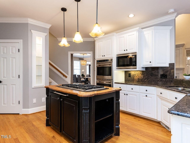 kitchen featuring dark cabinetry, light wood-style flooring, ornamental molding, appliances with stainless steel finishes, and white cabinetry