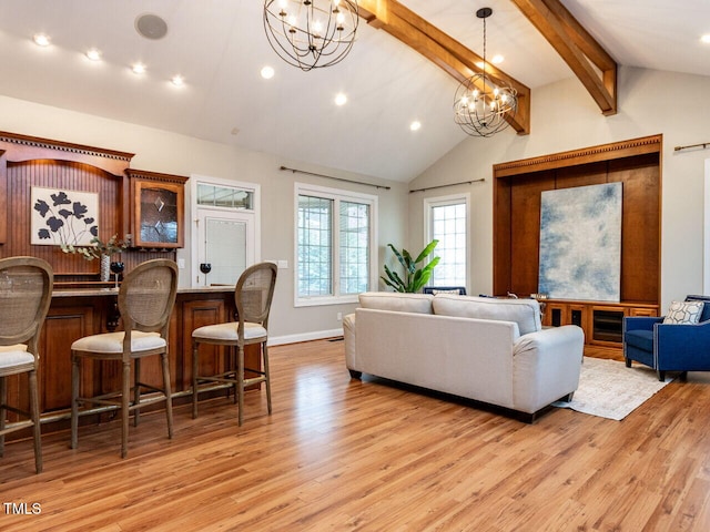 living room with a bar, an inviting chandelier, lofted ceiling with beams, and light wood finished floors