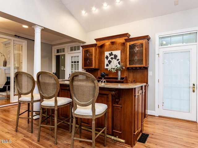 bar with visible vents, lofted ceiling, light wood-style flooring, decorative columns, and recessed lighting