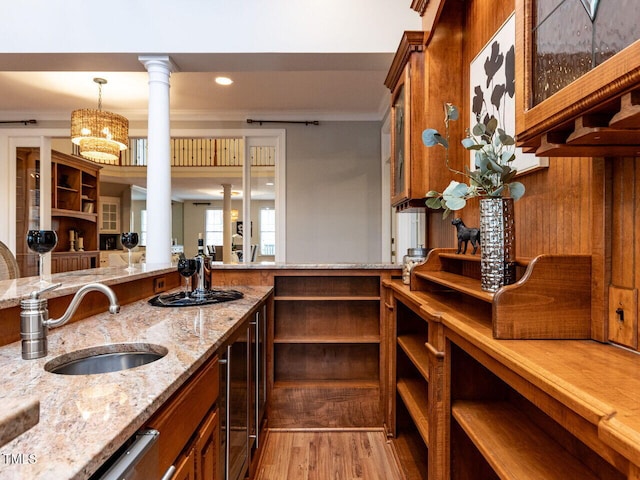 kitchen featuring light stone counters, glass insert cabinets, brown cabinets, and a sink