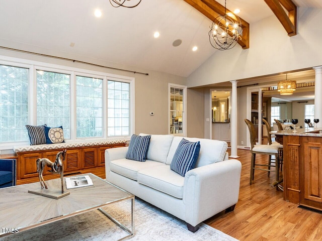 living room featuring light wood-type flooring, beam ceiling, a healthy amount of sunlight, and ornate columns