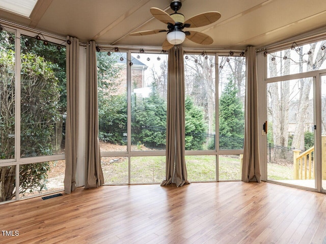 unfurnished sunroom featuring visible vents and ceiling fan