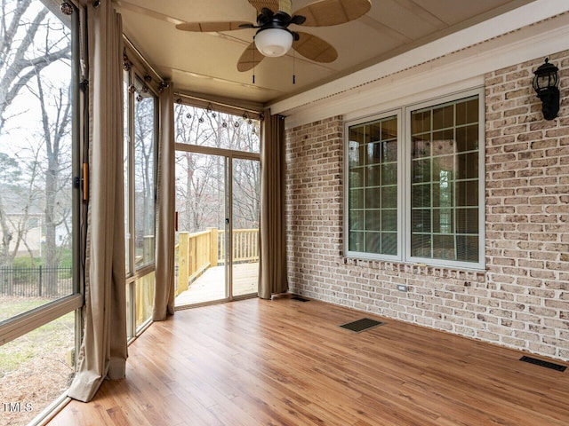 unfurnished sunroom featuring a ceiling fan, visible vents, and a healthy amount of sunlight