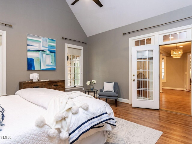 bedroom with baseboards, high vaulted ceiling, wood finished floors, and ceiling fan with notable chandelier